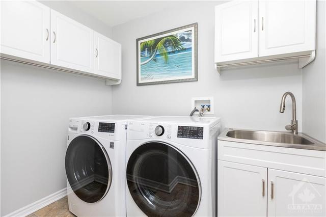 Main level is conveniently complete with a laundry room featuring overhead storage, sink, and racks. | Image 8