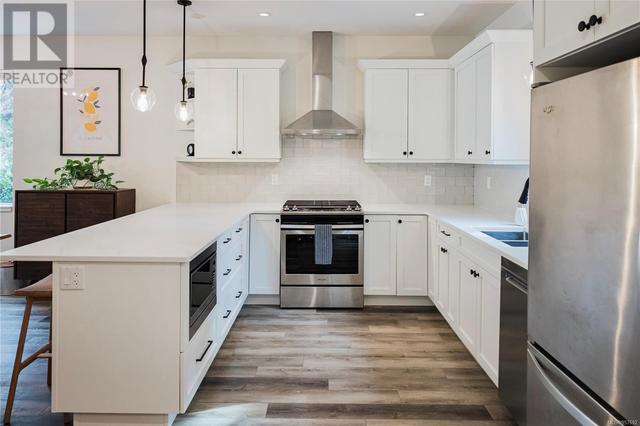 Tastefully appointed kitchen equipped with shaker-style cabinets adorned with modern hardware, alabaster quartz counters, stainless appliances w/propane range inviting warmth and effortless elegance | Image 15