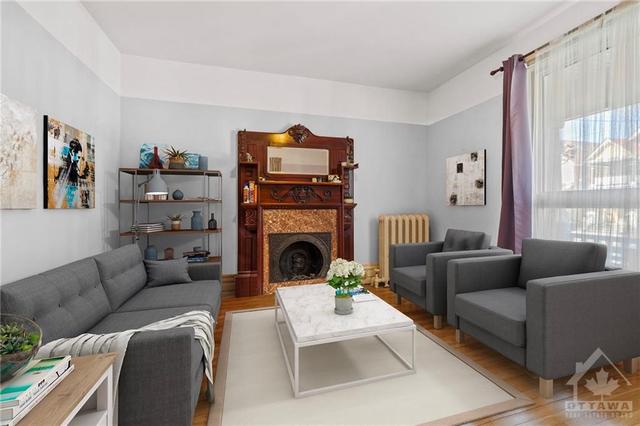 Unit 1-2 bedrooms Main floor living room. Spacious and bright with a large window. 9' ceilings, hardwood floors. Decorative fireplace. Virtually staged. | Image 3