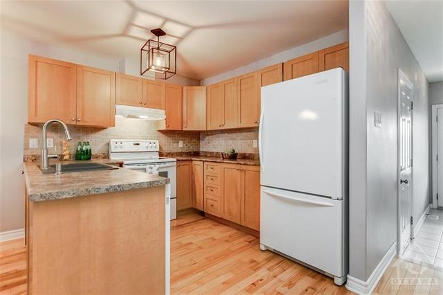 The kitchen features warm wood shaker style cabinets. | Image 4