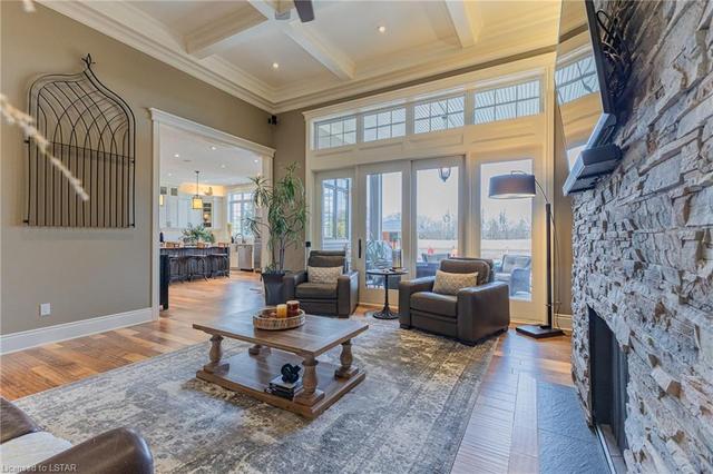 The great room is showcased with a striking 14' coffered ceiling and stone floor-to-ceiling fireplace. Enjoy 8' glass sliding doors leading to the back patio and custom built-ins | Image 16