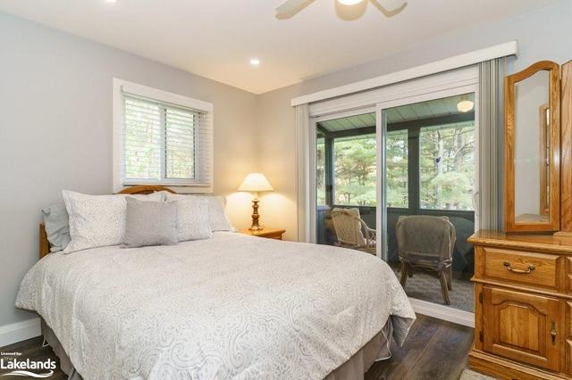 Primary bedroom with walkout to screened Muskoka Room that runs along the entire length of the cottage. | Image 26