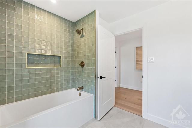 The second floor bathroom features a custom white oak vanity with Silestone quartz; a modern oversized soaker tub with built in niche and a timeless handmade green tile. Behind the door is a large | Image 21
