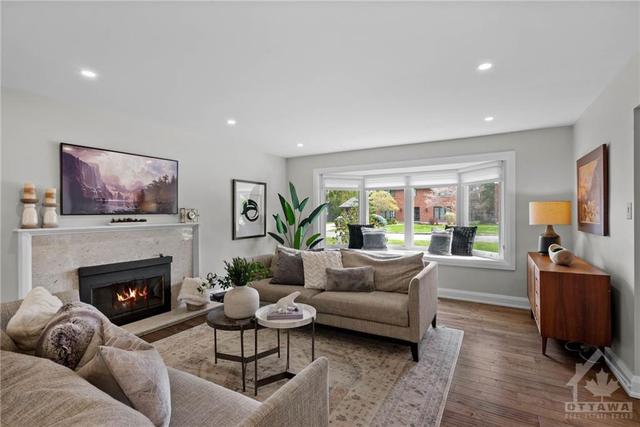 The main living room features a large bay window and an updated wood fireplace. | Image 4