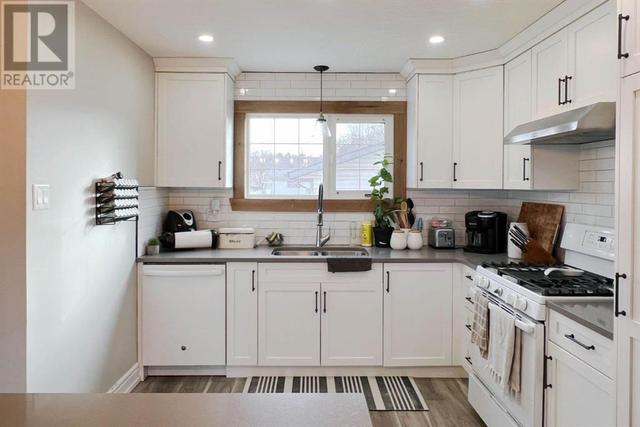 Gorgeous recently renovated kitchen with white cabinetry extending to the ceiling, subway tile backsplash, quartz counters and a gas stove | Image 3