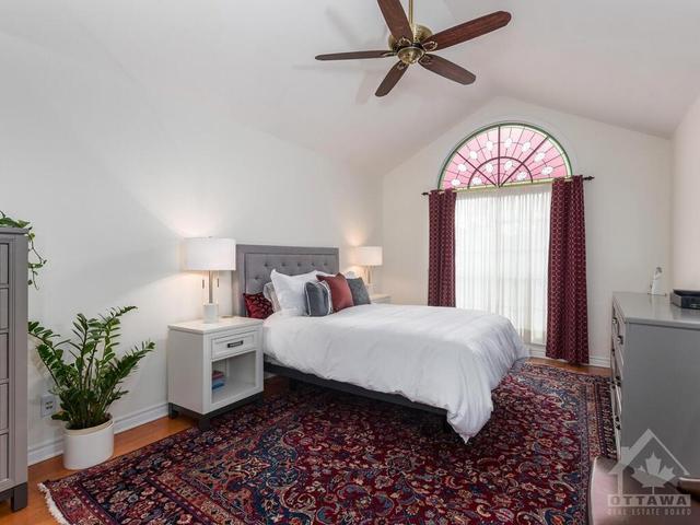 Spacious main floor primary bedroom with vaulted ceiling, ceiling fan, hardwood flooring and pretty window! | Image 15