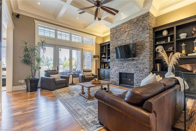 The great room is showcased with a striking 14' coffered ceiling and stone floor-to-ceiling fireplace. Enjoy 8' glass sliding doors leading to the back patio and custom built-ins | Image 14
