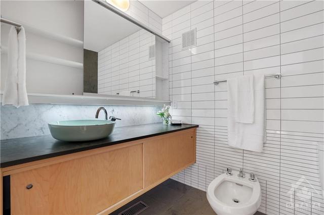 4pc en-suite bathroom - floating style vanity and bowl sink, bidet, and understated tile work done in geometric style designs, slate floors. | Image 20