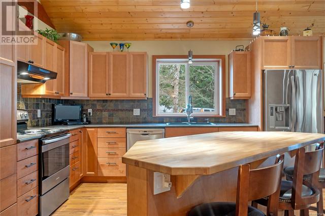 the home offers a Westcoast design and inviting open floor plan with vaulted wood ceilings.  Here's the kitchen with large island & eating counter & under cabinet lighting | Image 2