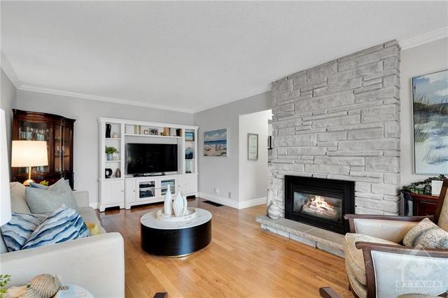 Impeccably maintained by the original owners, with plenty of natural light. The living room is spacious with a cozy fireplace. | Image 7