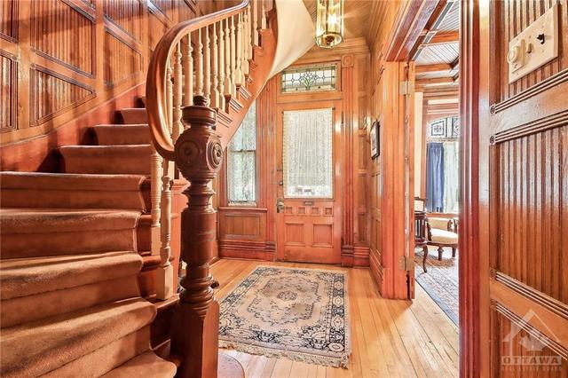 Rich wood panelling incases a spacious front entrance, curved staircase leading to second floor. Note the exeptional , detailed wood finishings. A period craftsman delight. | Image 26