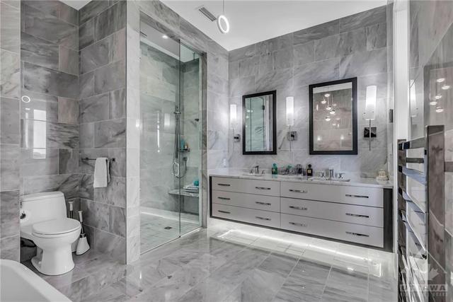 This hotel-inspired retreat is fully tiled and features a stand-alone soaker tub, a floating double vanity, walk-in glass shower and heated floors. | Image 21