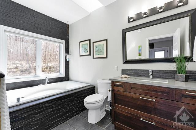 Primary suite 3-pc ensuite has soaker tub accented by ledger stone | Image 14