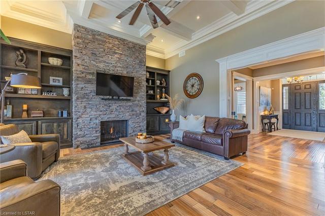The great room is showcased with a striking 14' coffered ceiling and stone floor-to-ceiling fireplace. Enjoy 8' glass sliding doors leading to the back patio and custom built-ins | Image 15