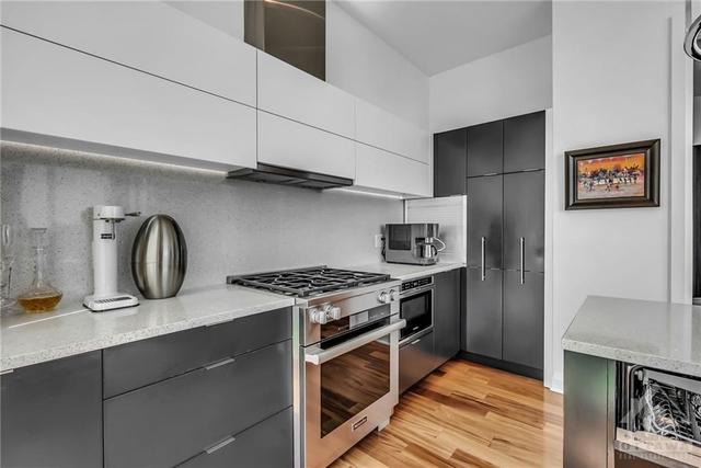 two-toned cabinetry, gleaming quartz countertops and backsplash, gas stove | Image 6