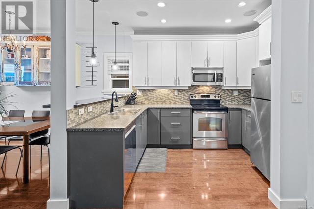 The kitchen features ample counter space and stainless steel appliances, with a newer dishwasher! | Image 6