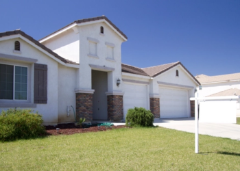 A house with a for sale sign on the front yard.