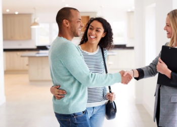 Young couple shaking hands with their real estate agent.