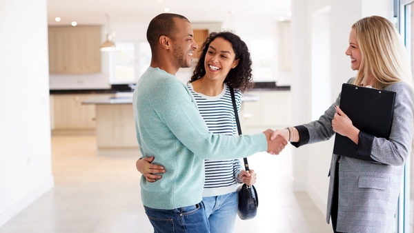 Young couple shaking hands with their real estate agent.