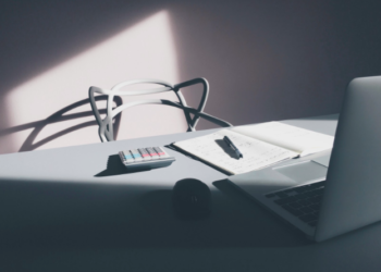 A laptop, notepad and calculator on a desk.