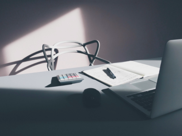A laptop, notepad and calculator on a desk.