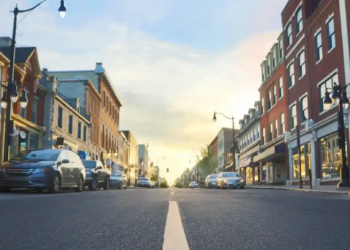 A city street lined with parked cars on both sides, showcasing urban life and traffic patterns.