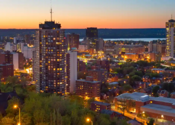 A city skyline at dusk, featuring silhouetted buildings against a colorful twilight sky.