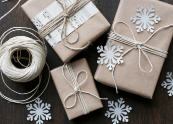Winter holiday gift wrapping with brown craft paper, twine, and snowflake decorations. Three boxes have thin twine bows.