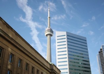 December TRREB Report Blog Hero, a view of the CN tower behind apartment buildings