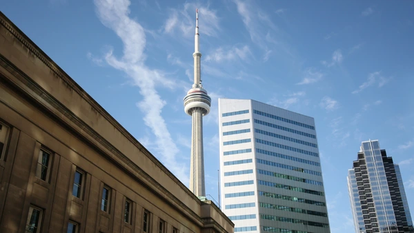 December TRREB Report Blog Hero, a view of the CN tower behind apartment buildings