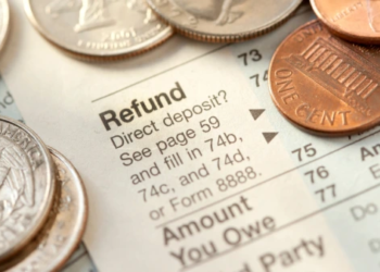 Close up of a tax refund document with coins spread on top of it.