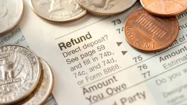 Close up of a tax refund document with coins spread on top of it.