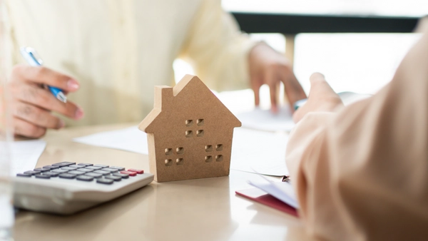 A picture of a calculator and a small wooden house.