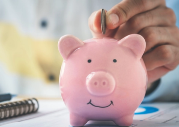 Someone puts a coin into a piggy bank.