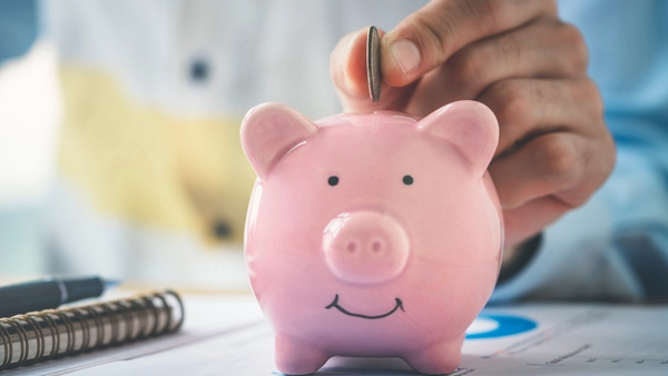 Someone puts a coin into a piggy bank.
