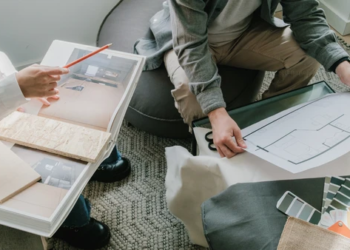 Two people look at blueprints, color options and pictures of a home.