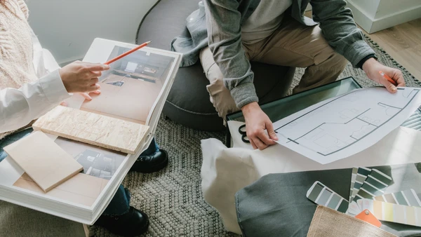 Two people look at blueprints, color options and pictures of a home.