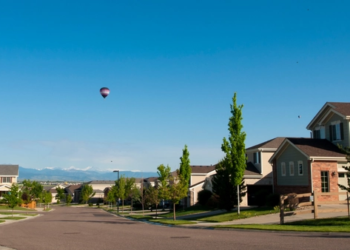 A neighbourhood in Canada on a sunny day with hot air balloons in the distance.