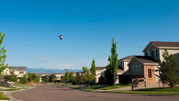 A neighbourhood in Canada on a sunny day with hot air balloons in the distance.
