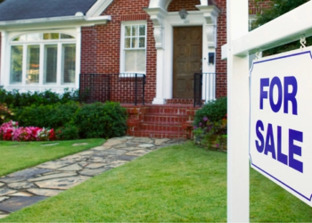 For sale sign in front of house.