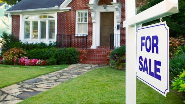 For sale sign in front of house.