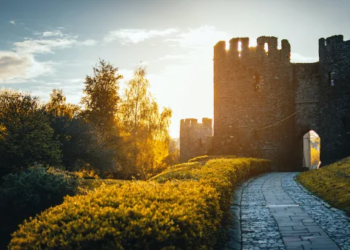 The sun sets behind an old stone castle.