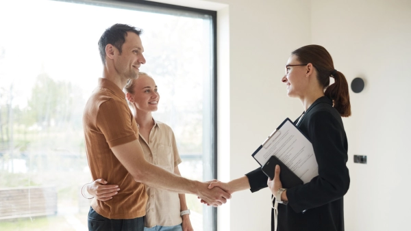A couple shakes hands with a real estate agent.