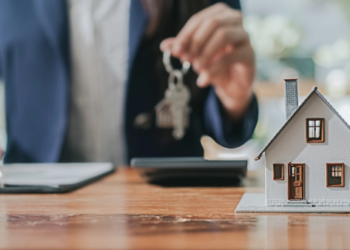 A small wooden house with someone holding some keys in the background.