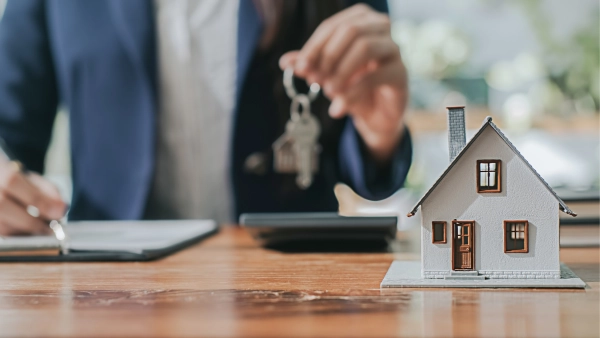 A small wooden house with someone holding some keys in the background.
