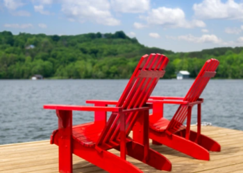 Two red Muskoka chairs on a dock.
