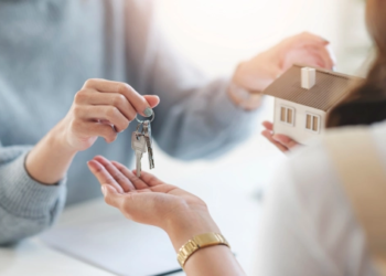 A person holding keys and a model house