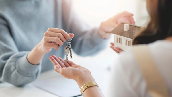A person holding keys and a model house
