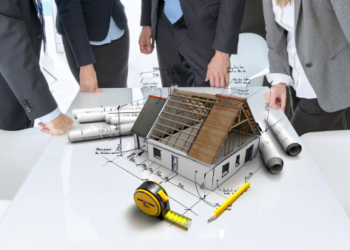 A group of people meeting around a table with an architectural model in the middle.