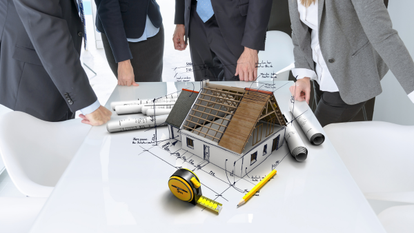 A group of people meeting around a table with an architectural model in the middle.